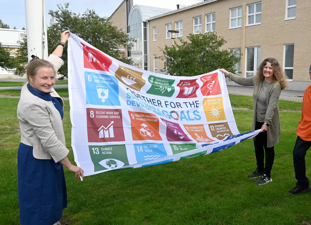 Nora Backlund (vas.) ja Tiina Saaresranta nostivat SDG-lipun salkoon, seuraamassa Lauri Numminen ja Tauno Linkoranta.